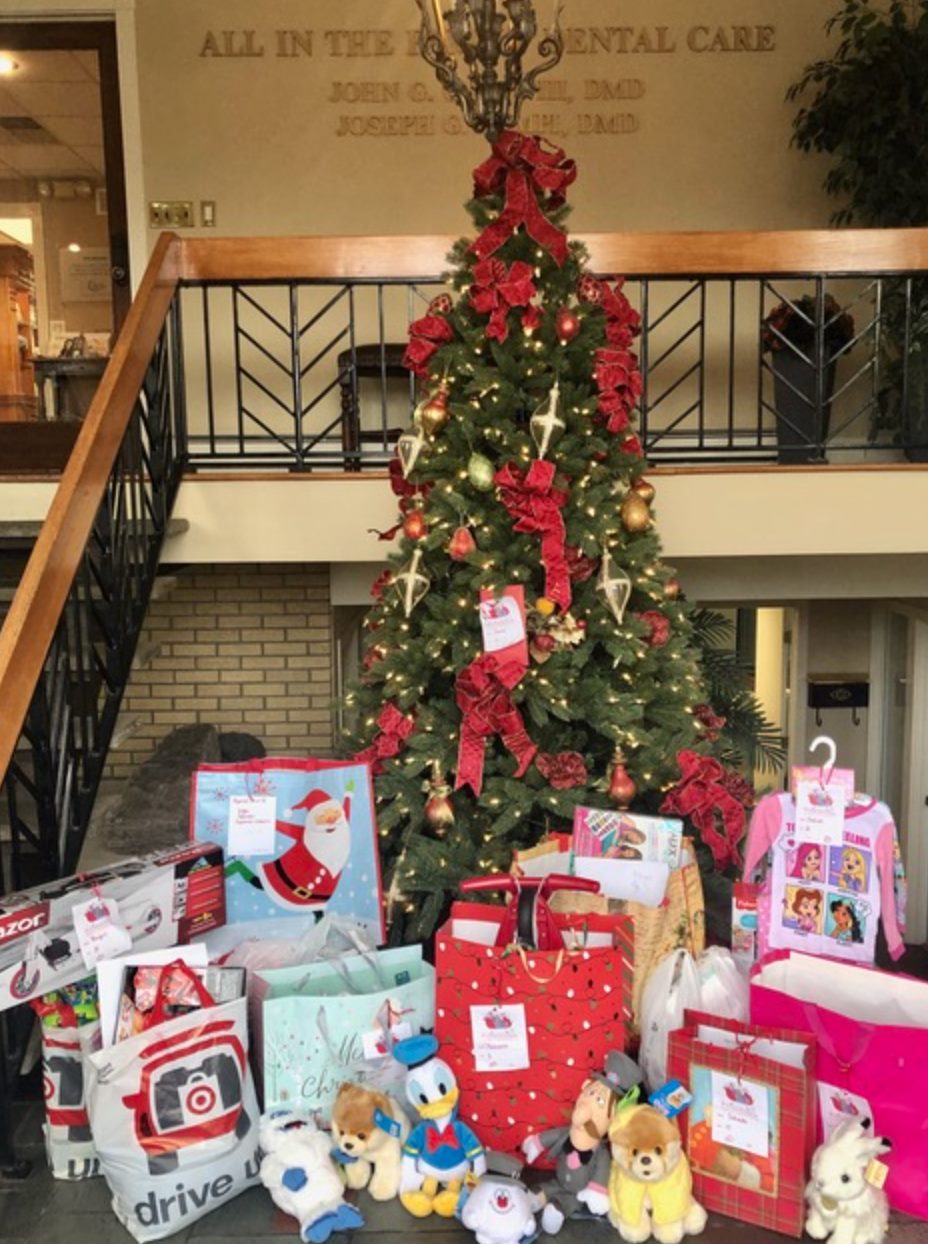 A christmas tree covered with decorations and surrounded with gifts