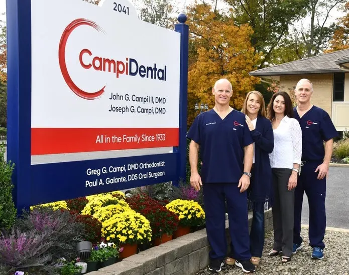 Campi Dental team in front of their sign and logo